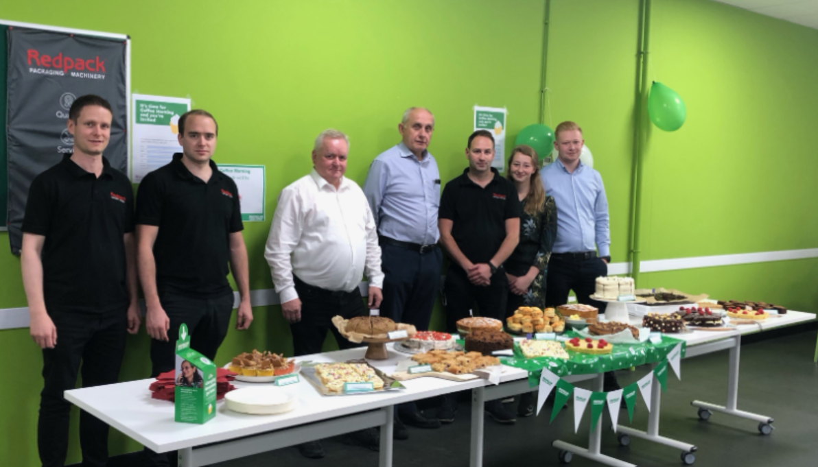 Redpack members and staff standing behind a table with the macmillan food